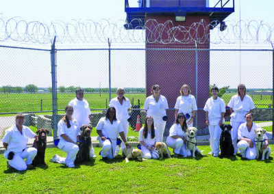 A group of people in white uniforms sitting on the grass.