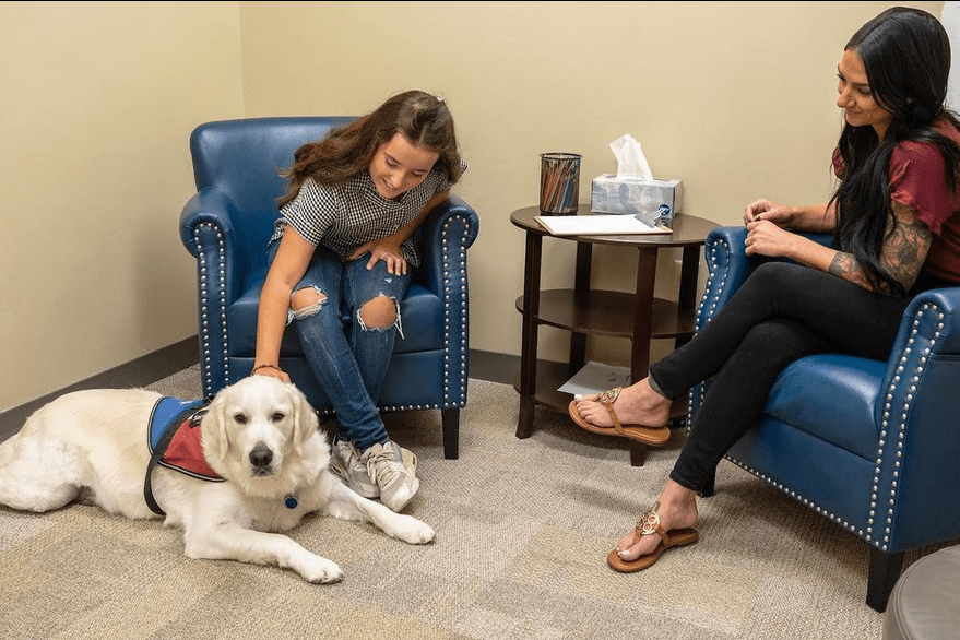 A woman sitting in front of two women with a dog.