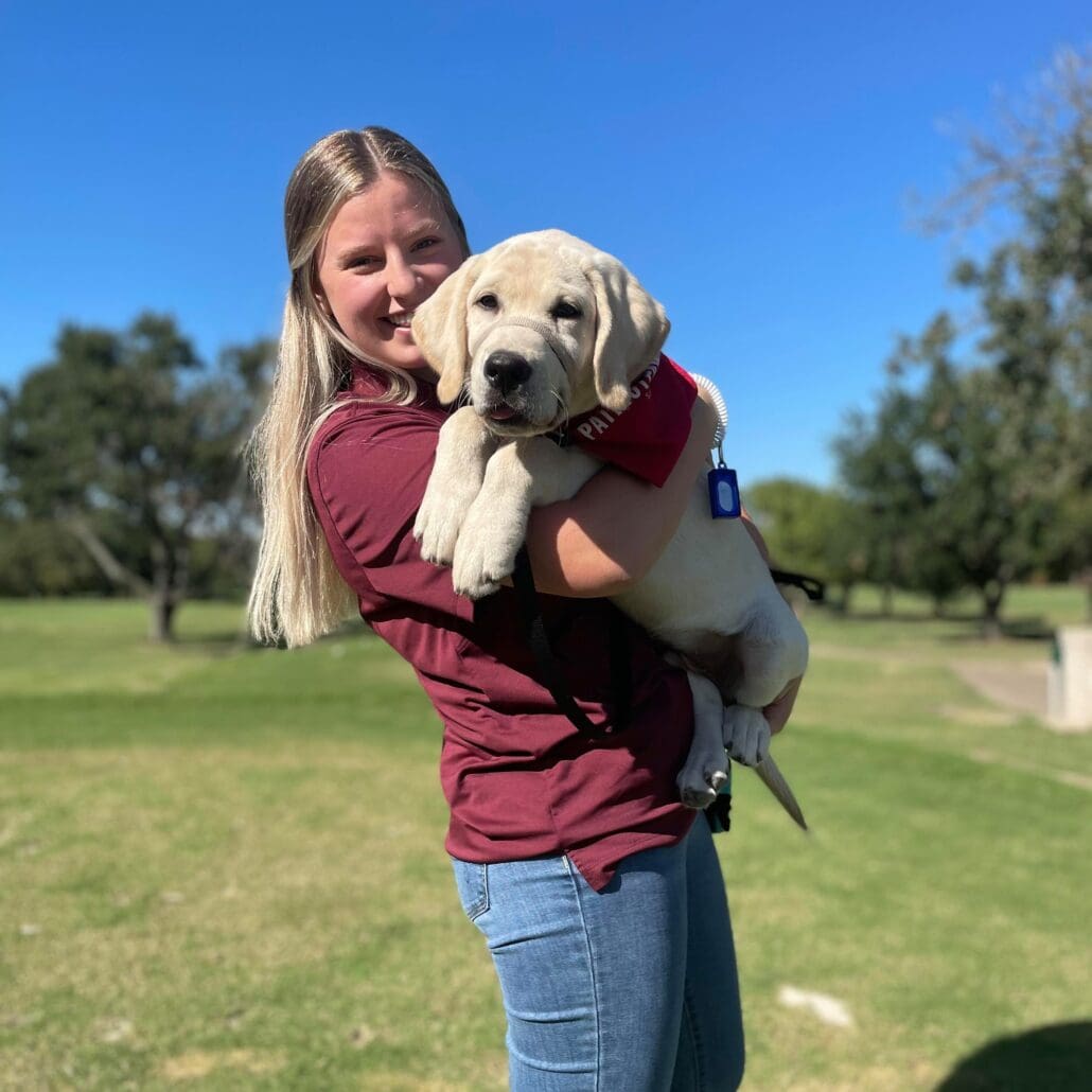 Woman holding adorable yellow lab puppy.